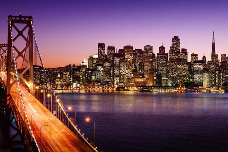 a bridge over water with a city in the background
