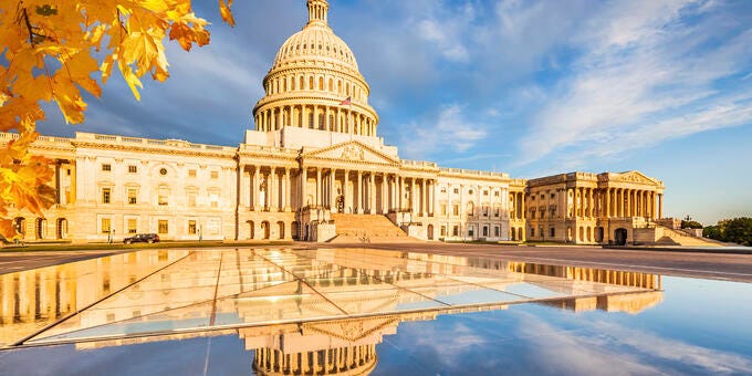 a large white building with a dome and a pool of water in front with United States Capitol in the background