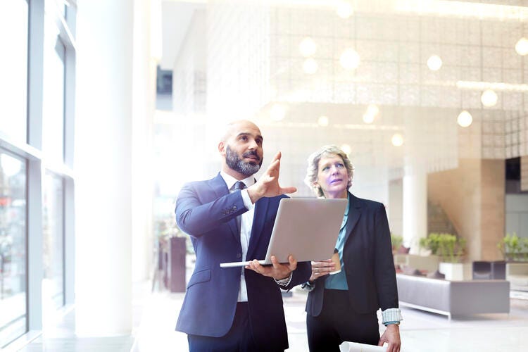 a man and a woman holding a laptop and smiling