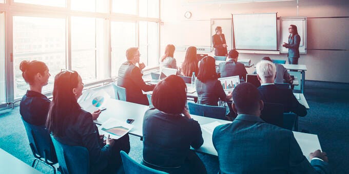 a group of people sitting in a room with a projector screen