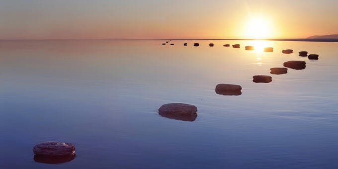 a body of water with rocks in it and the sun setting